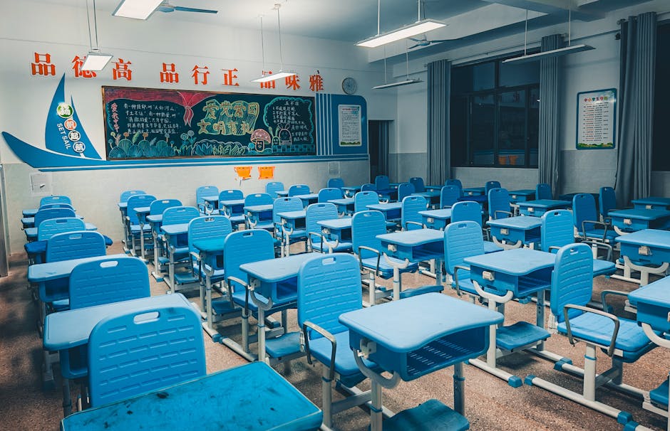 Spacious classroom with blue desks and vibrant decorated chalkboard, ready for students.