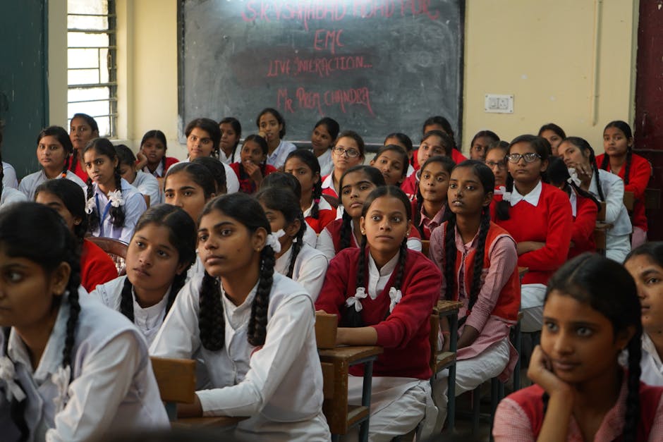 Group of Indian schoolgirls in uniform attentively listening in a classroom setting
